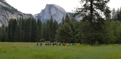 Summer Day Camp Campers walking through Yosemite Valley with half dome in the background.