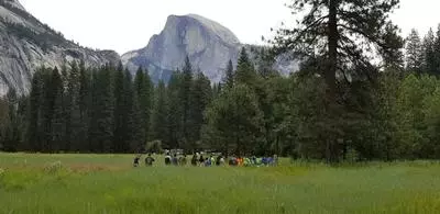 Summer Day Camp Campers walking through Yosemite Valley with half dome in the background.